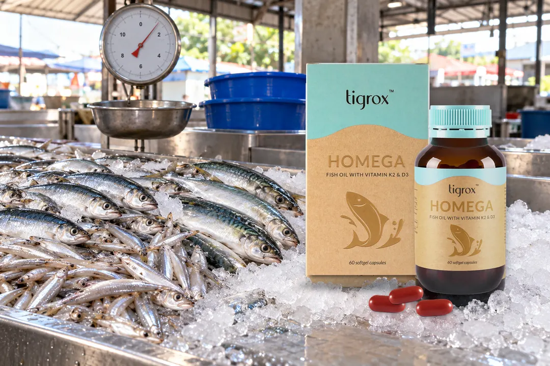 The HOMEGA box and bottle on the crushed ice of a morning fish stall, beside rows of small fish and the stall's hanging scale.