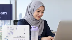 Seorang wanita bertudung tersenyum di hadapan komputer riba di pejabat, botol shaker dan kotak Kuro Daitto di atas meja, menara Kuala Lumpur di belakang. Kenyang sehingga 4 jam. Hasil berbeza bagi setiap orang.