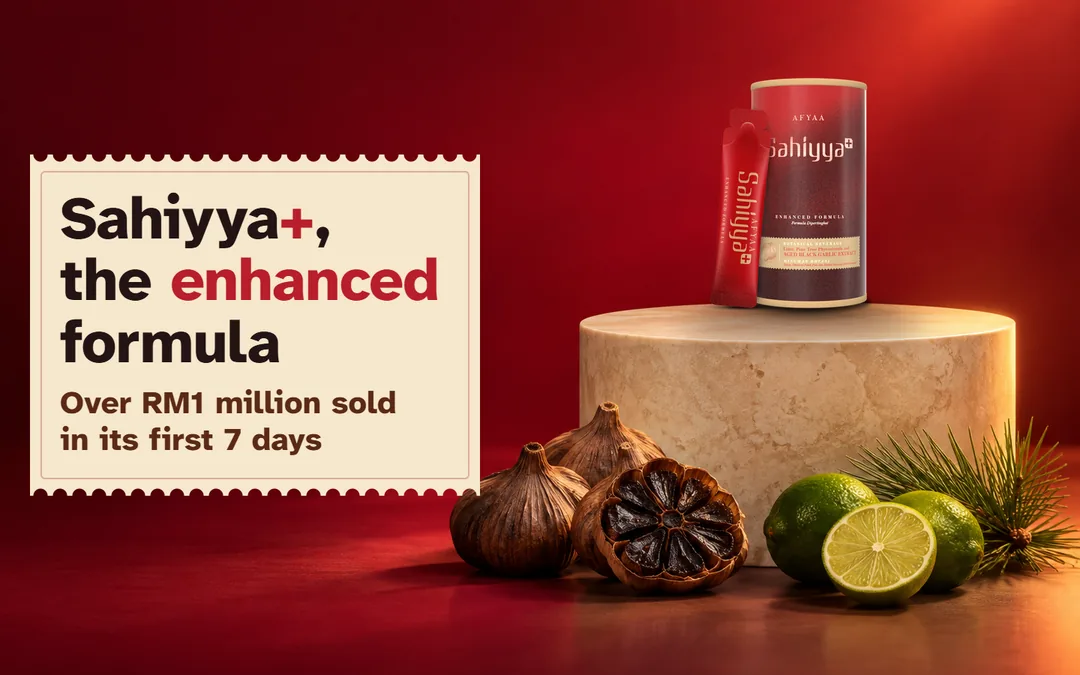 The AFYAA Sahiyya+ tin and a sachet on a cream plinth with aged black garlic, limes and pine. Sahiyya+, the enhanced formula. Over RM1 million sold in the first 7 days.