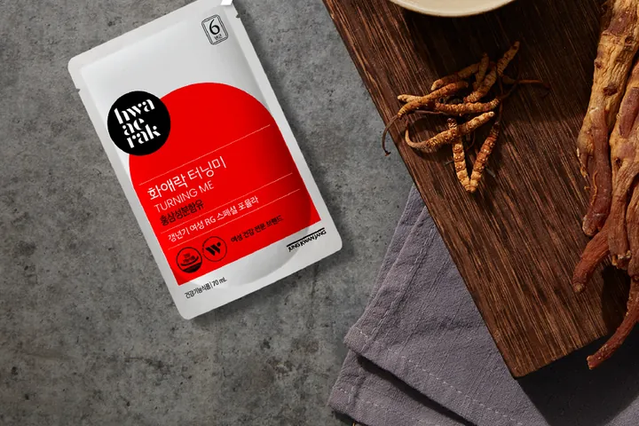 A Hwa Ae Rak Turning Me sachet beside Korean red ginseng roots and a bowl of red ginseng