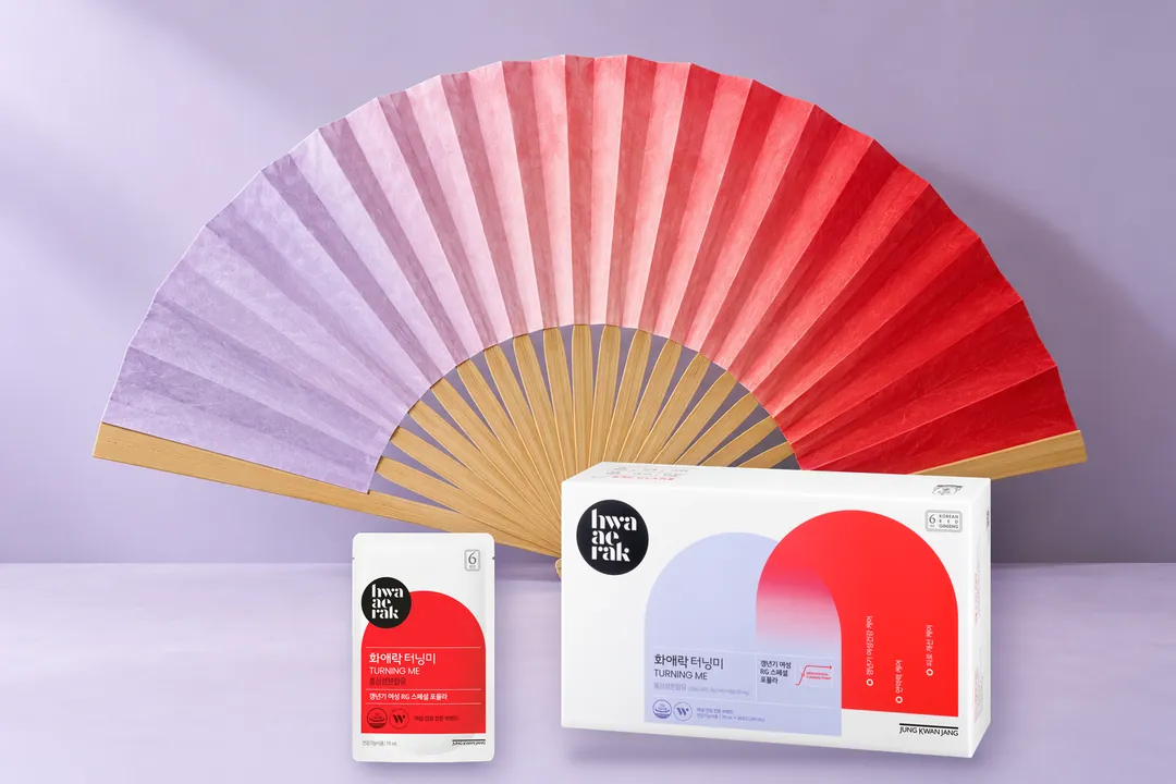 A box of Hwa Ae Rak Turning Me and a sachet in front of a fully open Korean folding fan of lilac and red paper