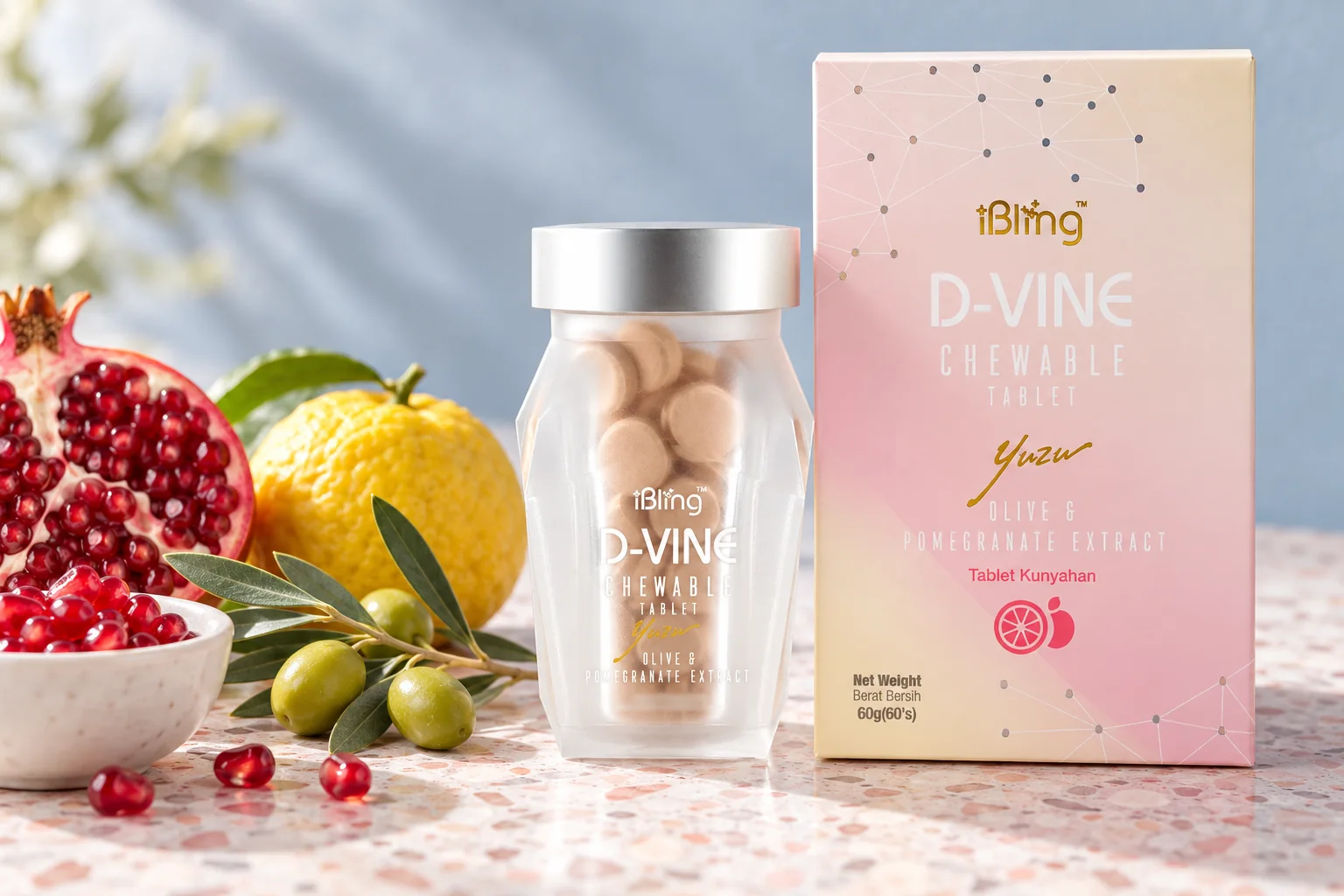 The D-VINE box and jar beside a halved pomegranate, olives and a yuzu on pink-grey terrazzo